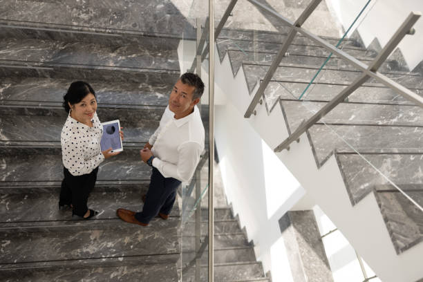 カメラを見ている階段の中で中国人のビジネスウーマンと日本のビジネスマン - businessman high angle view two people looking at camera ストックフォトと画像