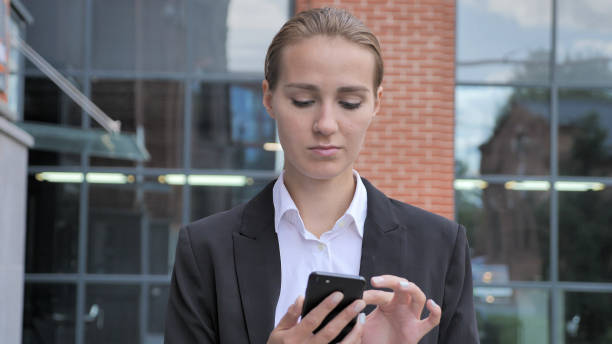 istock Walking Businesswoman Busy Using Smartphone Outside Office 1338933502