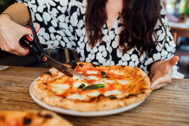 istock Woman using pizza cutter scissors for cutting pizza 1338935496