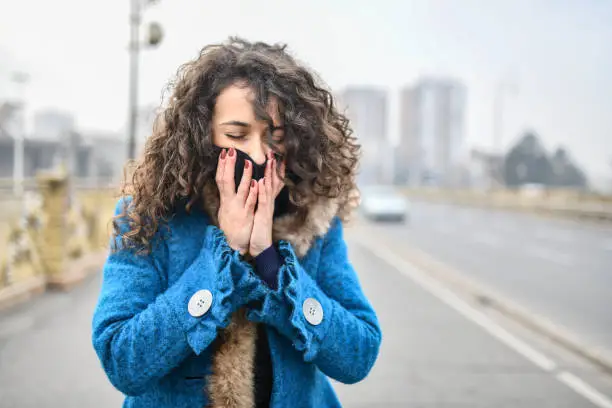 Photo of Female Struggling With Bad Air Pollution While Walking Through City