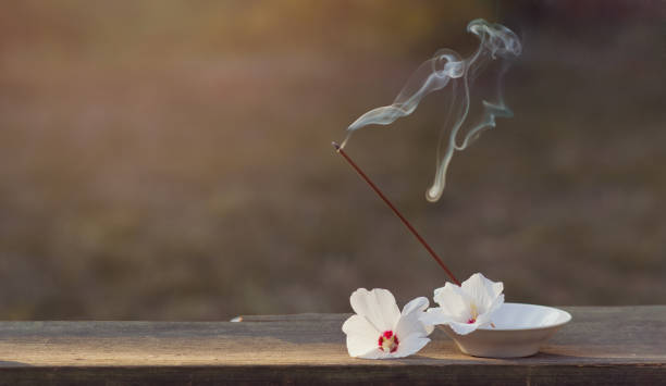 istock Incense sticks with smoke for spiritual practices outdoors and beautiful white jasmine flowers on a wooden surface. Banner for design. The concept of peace and inner balance. Copyspace 1338936000