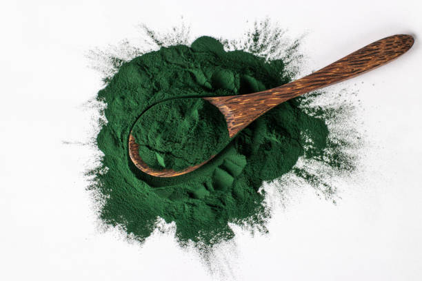istock Organic spirulina algae powder in wooden spoon on white background. 1338936649