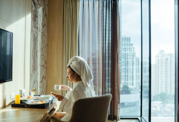 signora che mangia la colazione nella camera d'albergo - hotel wireless technology bedroom hotel room foto e immagini stock