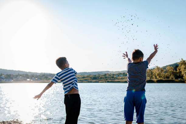 Two cute blond children, boy and girl on river bank