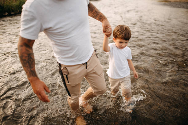 Summer family outdoor activities. Father teaches his little son to swim in lake.
