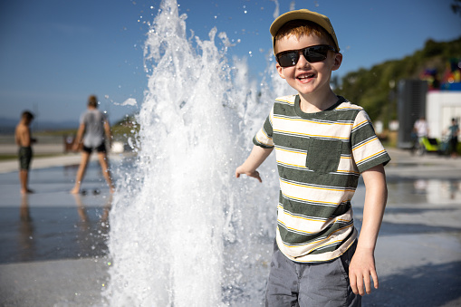 Cute Redhead Boy Playing in the Water Fountain, Fontaine du Quai Paquet, Lévis, Quebec, Canada. He is playing in the water with his clothes on and will all be wet.