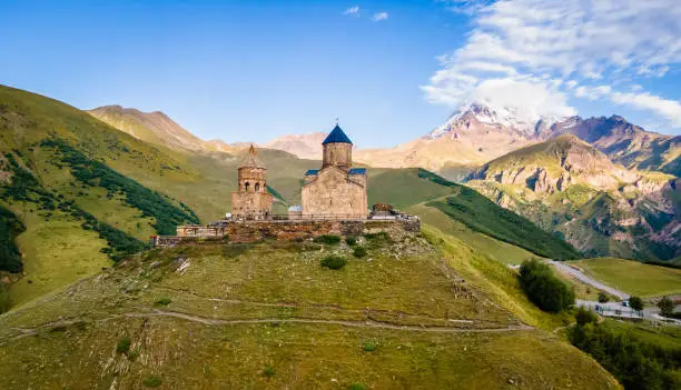 Aerial close up view of Kazbek mountain and Gergeti Trinity Church in Georgia at sunrise in summer