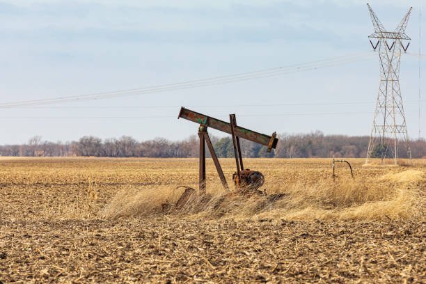 Old, orphaned oil well pump in farm field.  oil well abandonment, decommission, and oil production concept background, no people oil well stock pictures, royalty-free photos & images