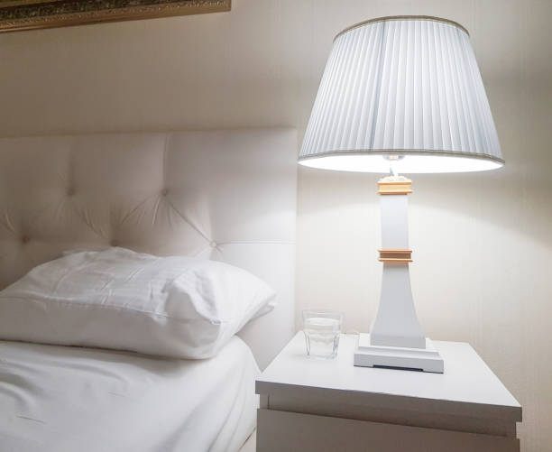 istock Luxury modern design of a bright bedroom with a bedside table and a night light and a pillow on the bed, preparing for bed, a glass of water 1338957582