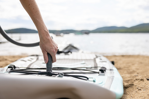 Woman Inflating Paddleboard SUP at the Beach in Summer, Quebec.