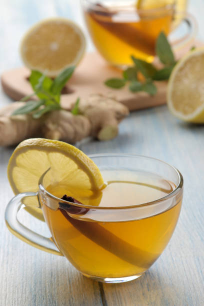 istock Composition with green hot tea with cinnamon, lemon and ginger on a blue wooden background 1338957838