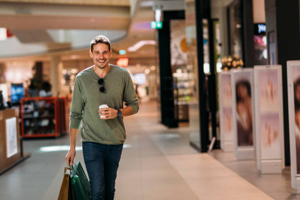 Shopping Handsome man walking with shopping bags in a mall mall walker stock pictures, royalty-free photos & images