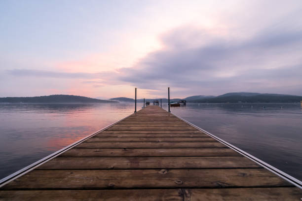 Watching Summer Sunset on the Pier by the Lake. View of Lac St-Joseph, Fossambault Sur Le Lac, Quebec, Canada at Sunset. The lake is a perfect mirror and there is an incredible sunset.