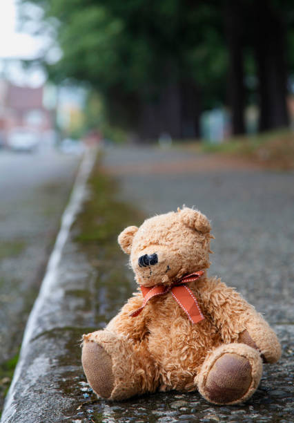 istock An abandoned, tattered teddy bear sits alone on a sidewalk 1338960641