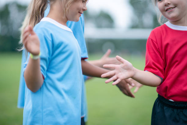 niñas dándose la mano en un partido de fútbol infantil - canadian football fotografías e imágenes de stock