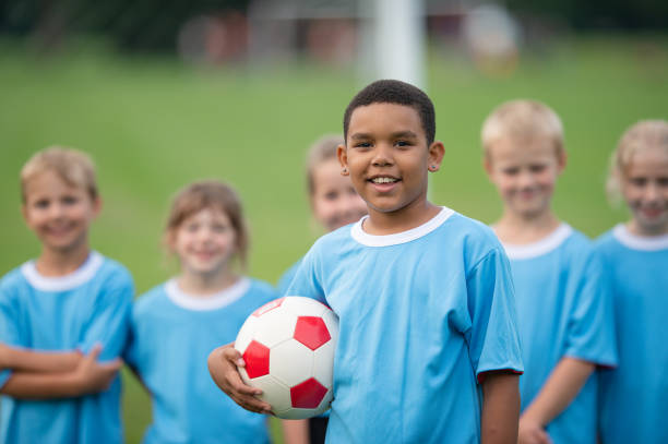 istock Young boy holding a soccer ball with his teammates 1338966096