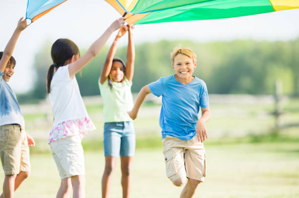 istock Caucasian boy smiling and running under a playground parachute 1338966974