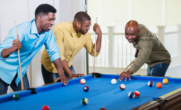 istock Three African-American men shooting pool, taking a shot 1338970296