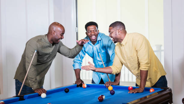istock Three African-American men shooting pool, low five 1338970312