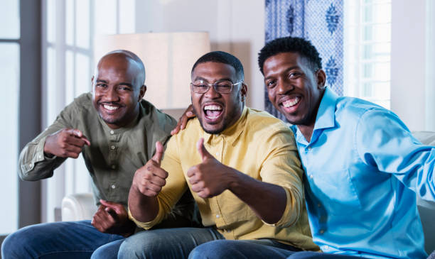 istock Three African-American men on couch laughing, thumbs up 1338970354