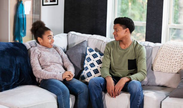 istock Mixed race twin teenagers conversing on sofa at home 1338970509