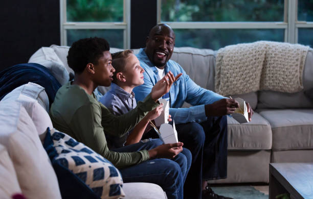 istock Blended family on couch watching TV, eating takeout 1338970548