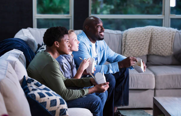 istock Blended family on couch watching TV, eating takeout 1338970549