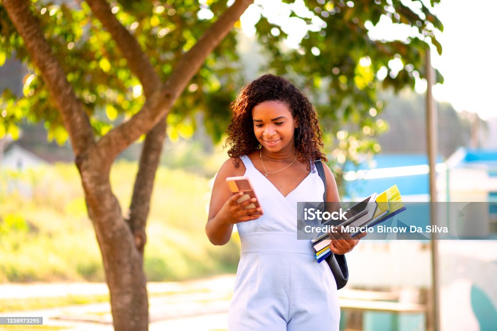 Student using mobile phone Young black student walking on college campus and and using your smart phone. E-learning concept. Mobile Phone Stock Photo