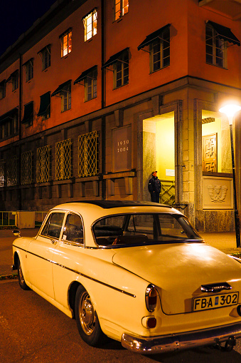 Koping, Sweden Sept 2, 2021 A man stands in a doorway on the Stora Torget or main square and a vintage Volvo Amazon car.