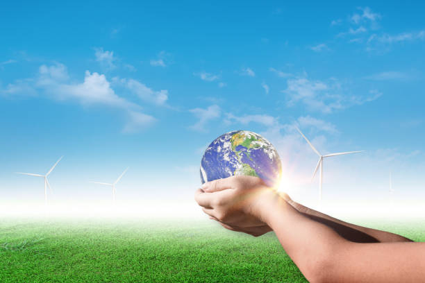 istock Hands holding earth, globe on wind turbine field against blue sky background. Environment concept 1338978860