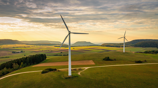 Aerial Panorama of Wind Turbines in green rural landscape during sunset. Green Energy, Alternative Energy Environment Concept Shot. Drone Point of View. Baden Württemberg, South Germany,  Germany, Europe