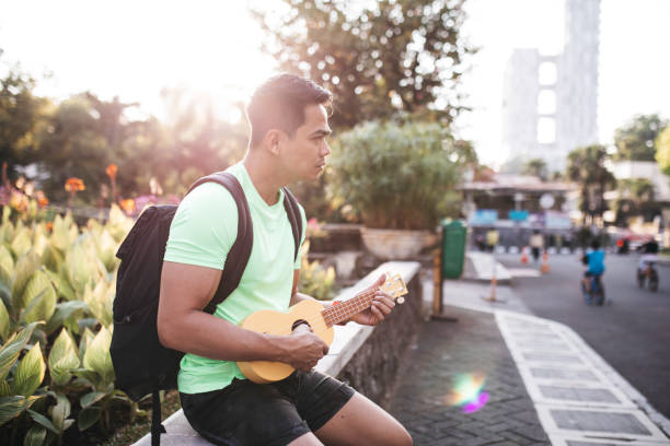 istock asian man playing guitar in the city 1338983234