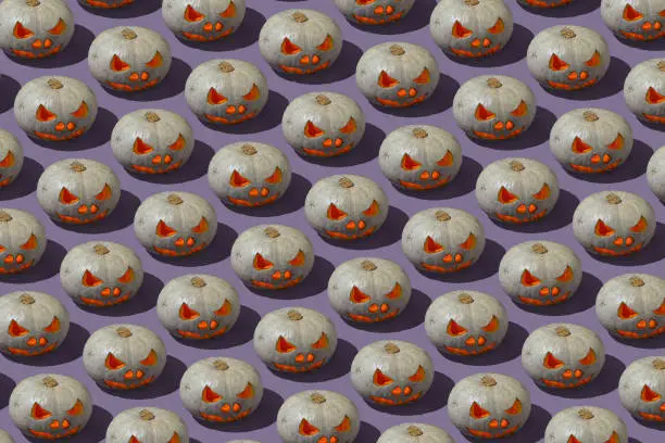 Photo of Pattern of Grey and orange Jack o' Lantern on violet background. Halloween pumpkin with lights and shadow