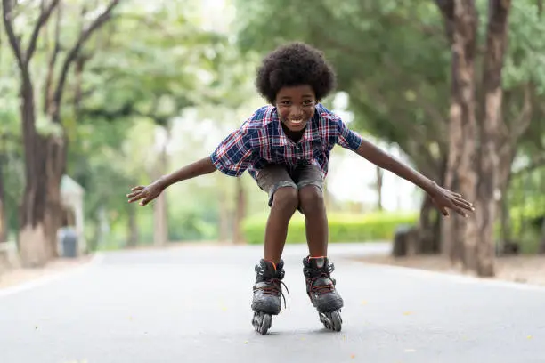 African American young boy riding on roller skates or roller blades at outdoor, Kid playing on roller skates.