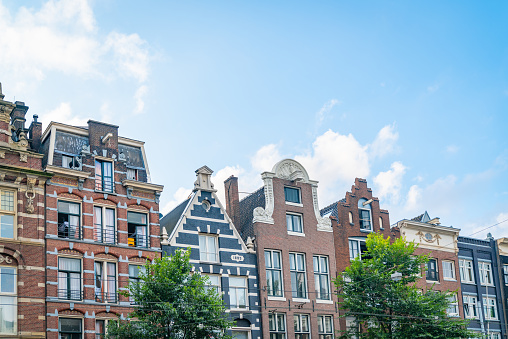 Row of typically Dutch canal houses with their variety and diversity of  facade and gable styles  in Amsterdam Holland.