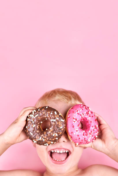 istock Smiling boy holding donuts in his hands. 1338990958
