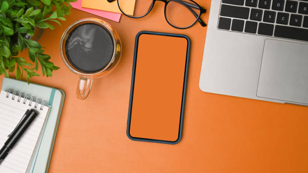 istock Top view mock up smart phone, coffee cup and computer laptop on orange background. 1338991208
