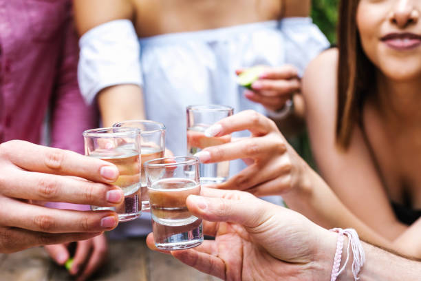 tequila shot, group of young latin friends meeting für tequila shot oder mezcal drinks making a toast in restaurant terrasse in mexiko lateinamerika - shot glass stock-fotos und bilder