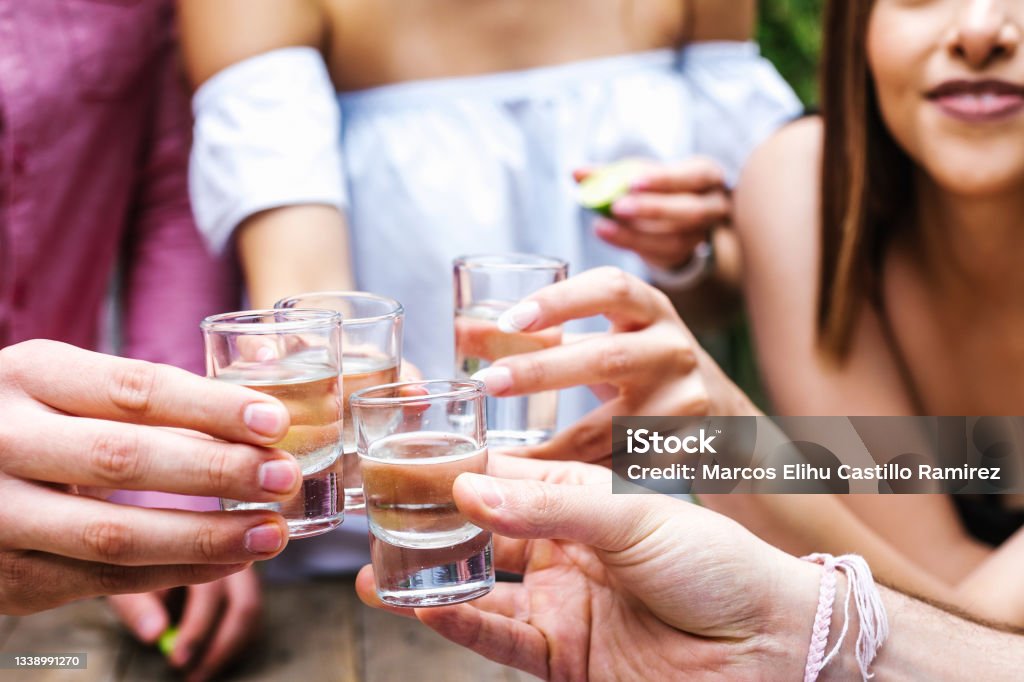 tequila shot, Group of Young latin Friends Meeting For tequila shot or mezcal drinks making A Toast In Restaurant terrace in Mexico Latin America Shot Glass Stock Photo