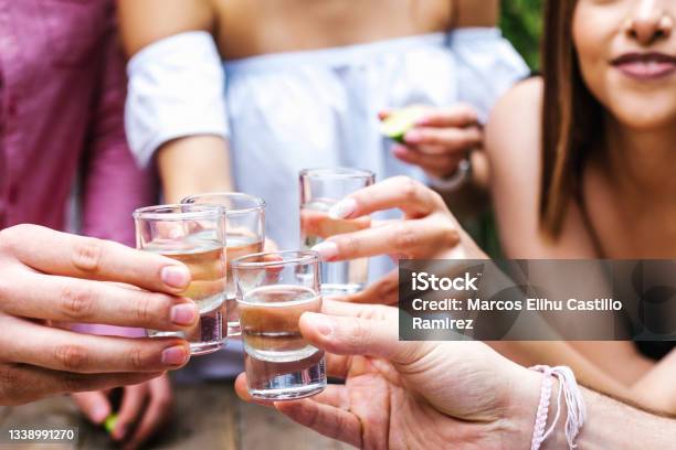 Tequila Shot Group Of Young Latin Friends Meeting For Tequila Shot Or Mezcal Drinks Making A Toast In Restaurant Terrace In Mexico Latin America Stock Photo - Download Image Now