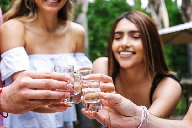 tequila shot, group of young latin friends meeting für tequila shot oder mezcal drinks making a toast in restaurant terrasse in mexiko lateinamerika - tequila slammer stock-fotos und bilder