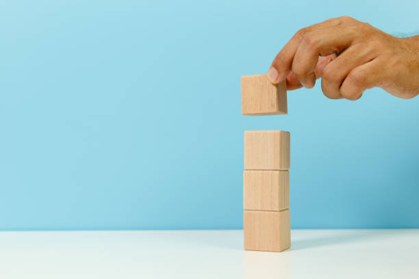 istock Hand holding stacking empty wooden cube block blue background.  management and choice concept. 1338991277