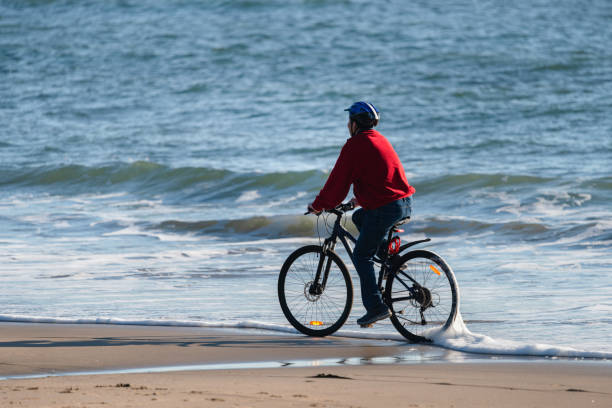 istock A cyclist riding along a sandy beach with waves rolling in, Milford beach, Auckland 1338992359