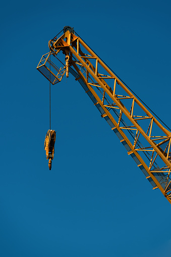 Bright yellow Industrial construction crane against the blue sky. Vertical format.