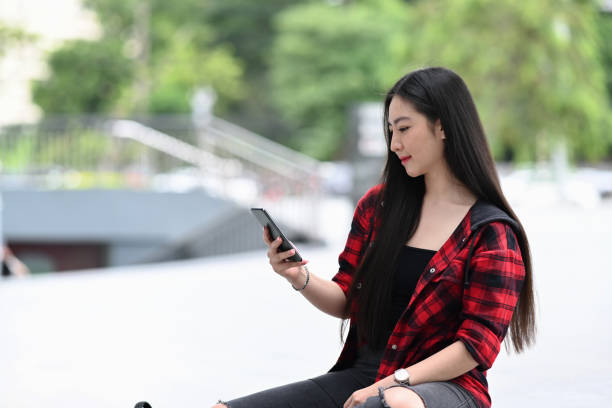 istock Young woman using smart phone and sitting at outdoors in city. 1338993201