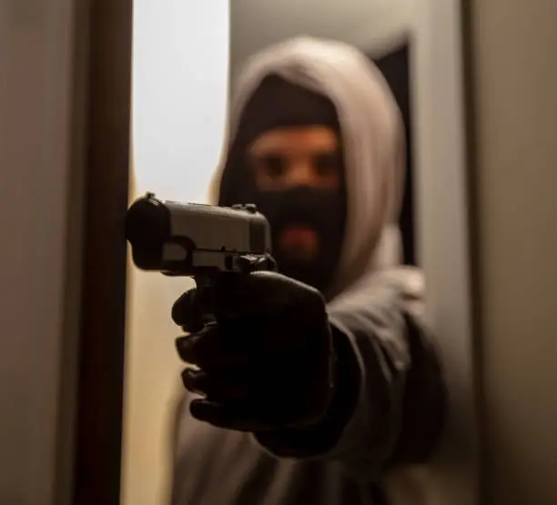 No Mercy concept. Marking with shooting from young man in black balaclava with grey hoodie holding gun. Action plan achieved, target, attack from hooded armed mafia killer criminal gangster terrorist.