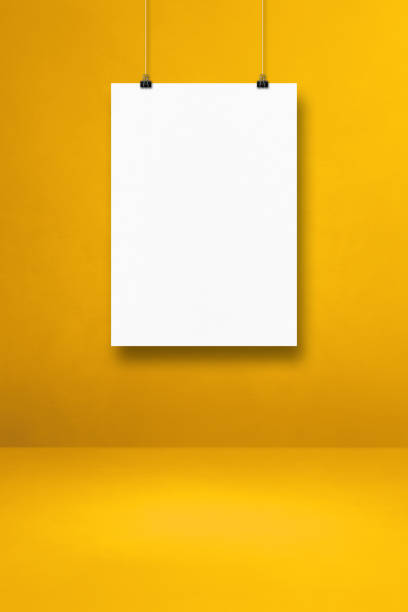 istock White poster hanging on a yellow wall with clips 1338994626