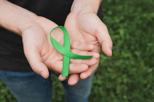 Mental health and medical concept. Man hands hold green mental health awareness ribbon. Close up lymphoma photos stock pictures, royalty-free photos & images