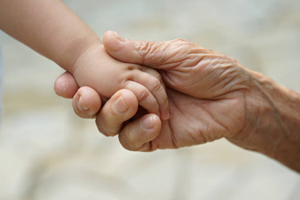 Grandma and granddaughter holding hands, close up stock photo