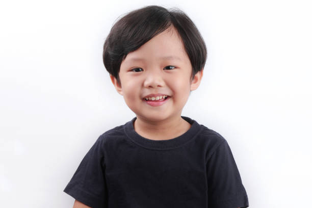 istock Little Asian Boy Smiling, Standing Against White Wall 1338995449